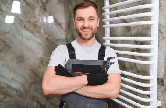 Heizungsmonteur mit Werkzeug vor Handtuchheizkörper im Bad von Ademi Sanitär in Delmenhorst