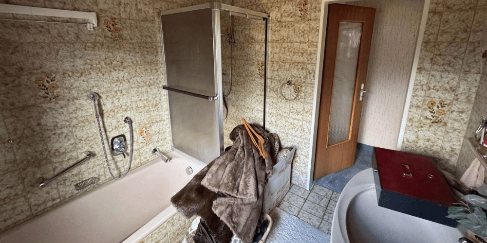 Altes Badezimmer mit Fliesen an den Wänden, Badewanne, Dusche und Waschtisch in Delmenhorst - Ademi Sanitär Delmenhorst - Heizung Badezimmer Klima Sanierungsbedürftiges Bad mit Fliesen, Badewanne und Dusche in Delmenhorst