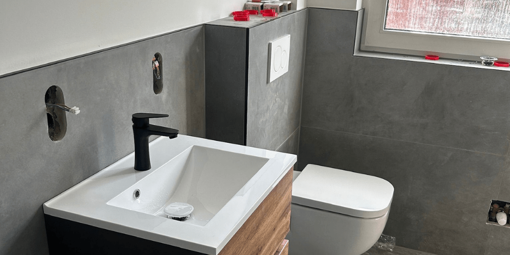 Modernes Gäste-WC mit neuem Waschbecken, schwarzer Armatur und eleganten Fliesen - Ademi Sanitär Delmenhorst - Heizung Badezimmer Klima Neues Bad mit stilvollem WC, Waschbecken und moderner Sanitärinstallation von Ademi Sanitär aus Delmenhorst